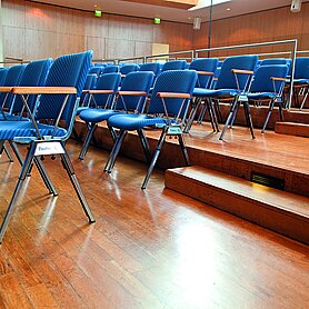 Detailaufnahme aus dem Maria-Theresia-Saal.Zu sehen sind einzelne Stuhlreihen mit blauen Stühlen und Stufen, die nach oben führen. Foto: Contrast Marketing für die Stadt Günzburg